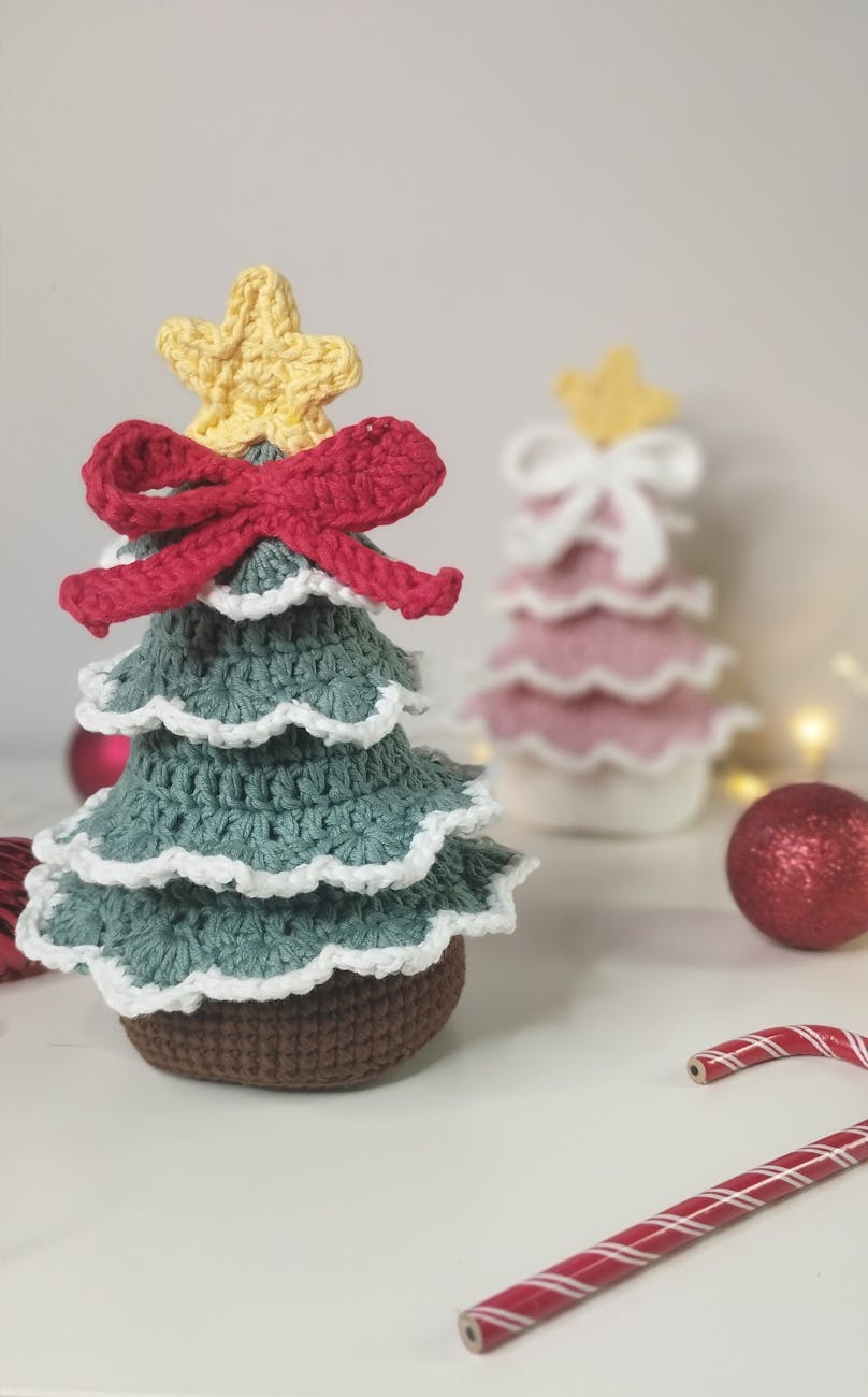 Charming crochet Christmas tree decoration with a star topper and red bow, perfect for festive home adornment.