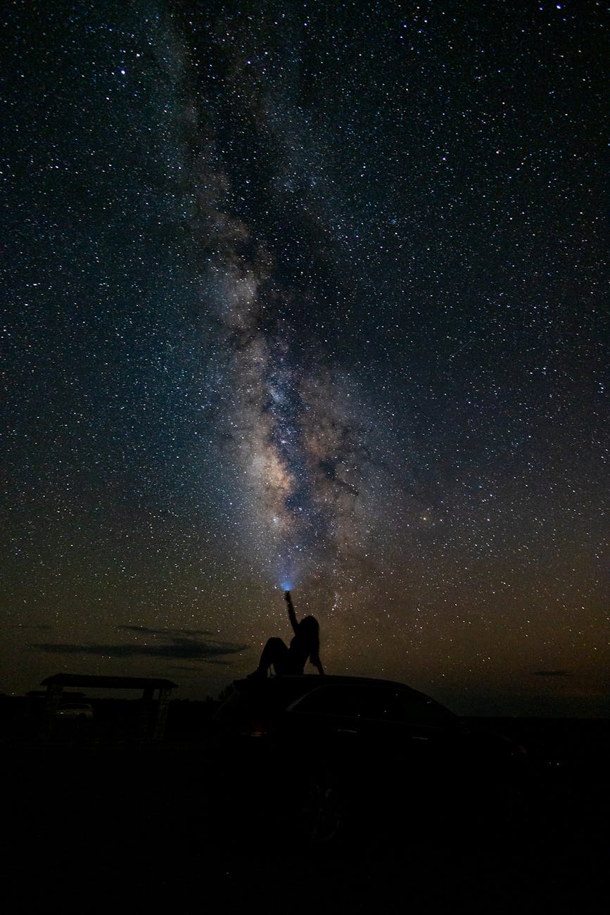 Silhouette of a person pointing at the Milky Way in a starry sky, captured in Sheffield, TX.