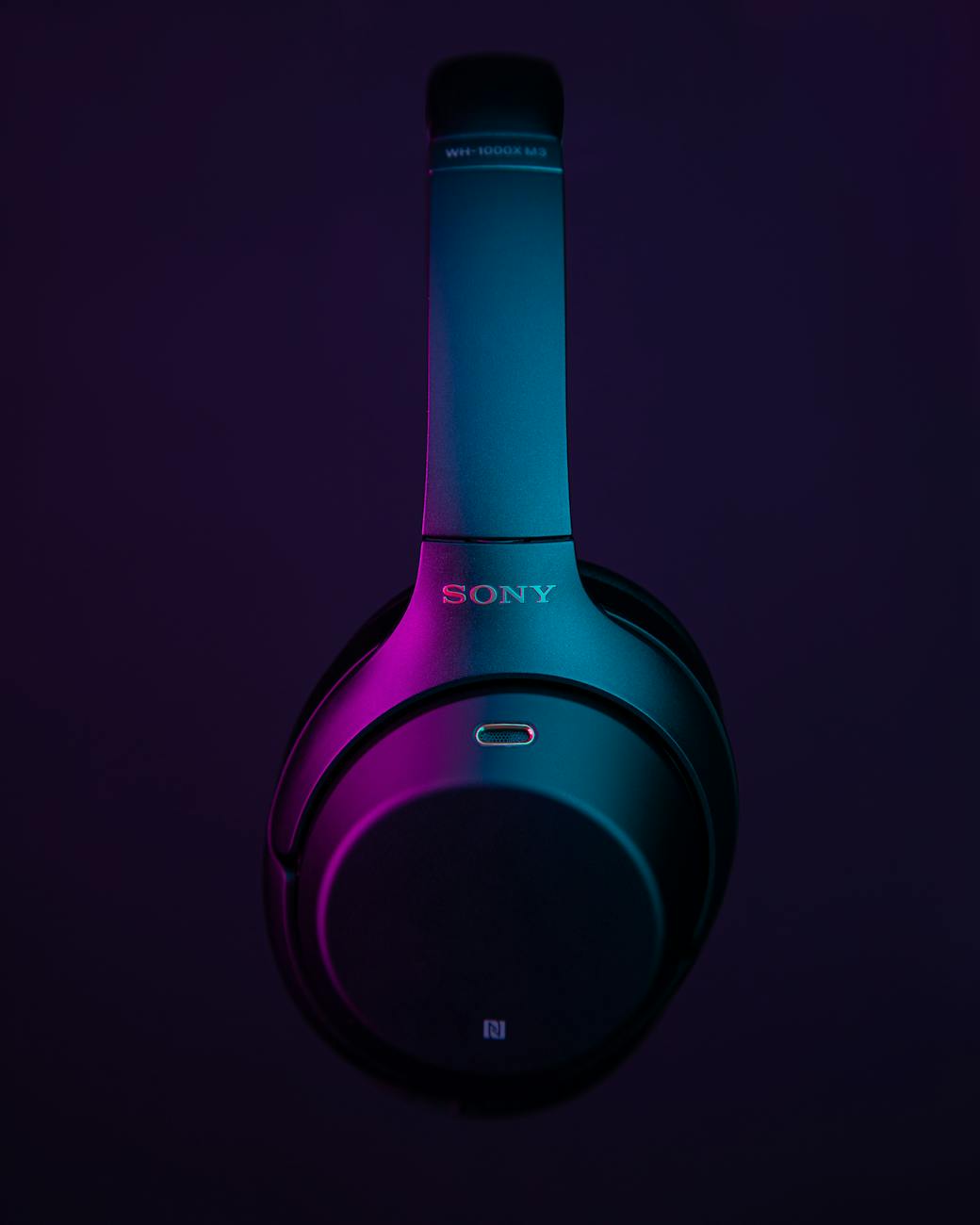 Close-up of sleek wireless headphones with a vibrant neon glow, emphasizing cutting-edge technology.