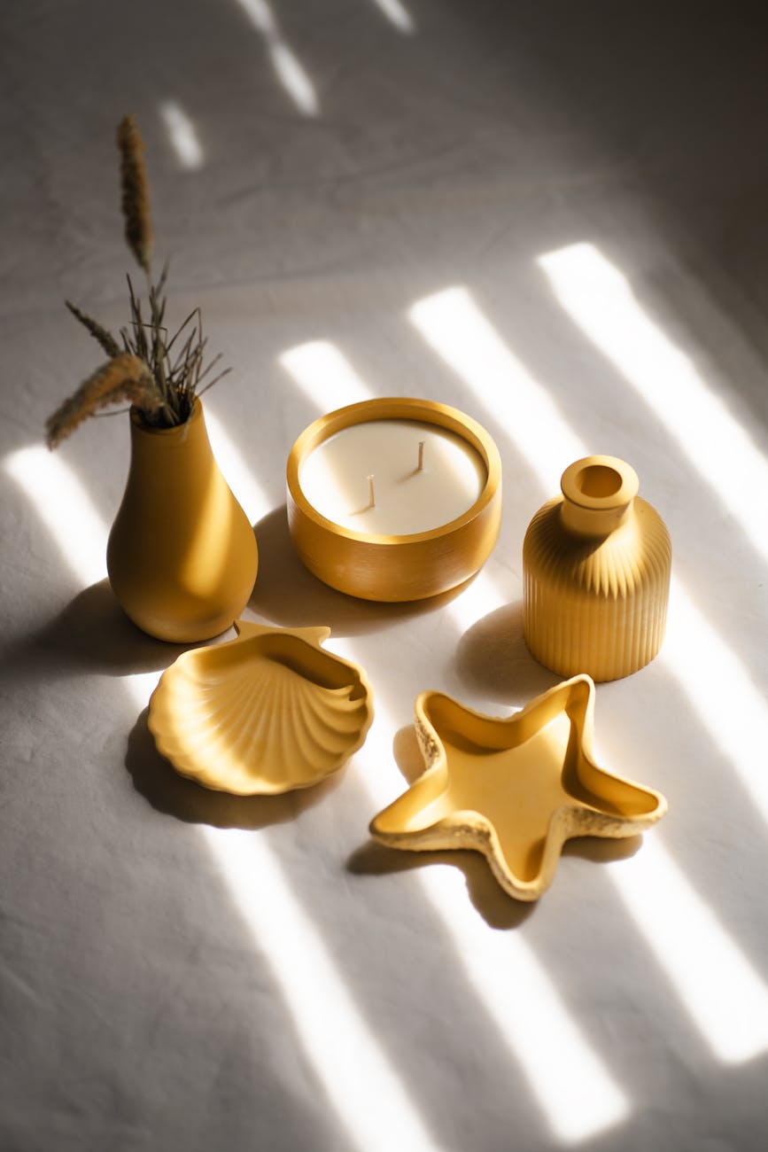Aesthetic setup of yellow ceramics and candle in natural light, perfect for home decor inspiration.